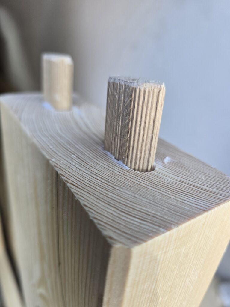 Nahaufnahme zweier geriffelter Holzdübel in einem Holzbauteil.