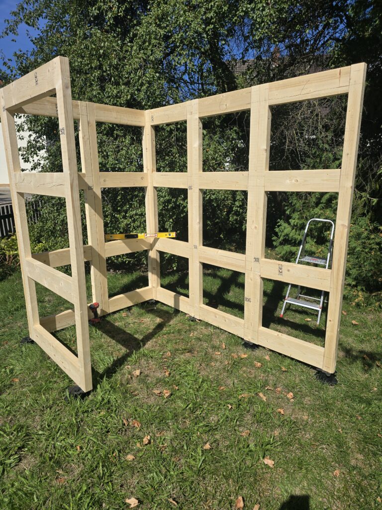 Aufgestellte Holzrahmen des Garden Cube im Garten, noch ohne Außenbekleidung.