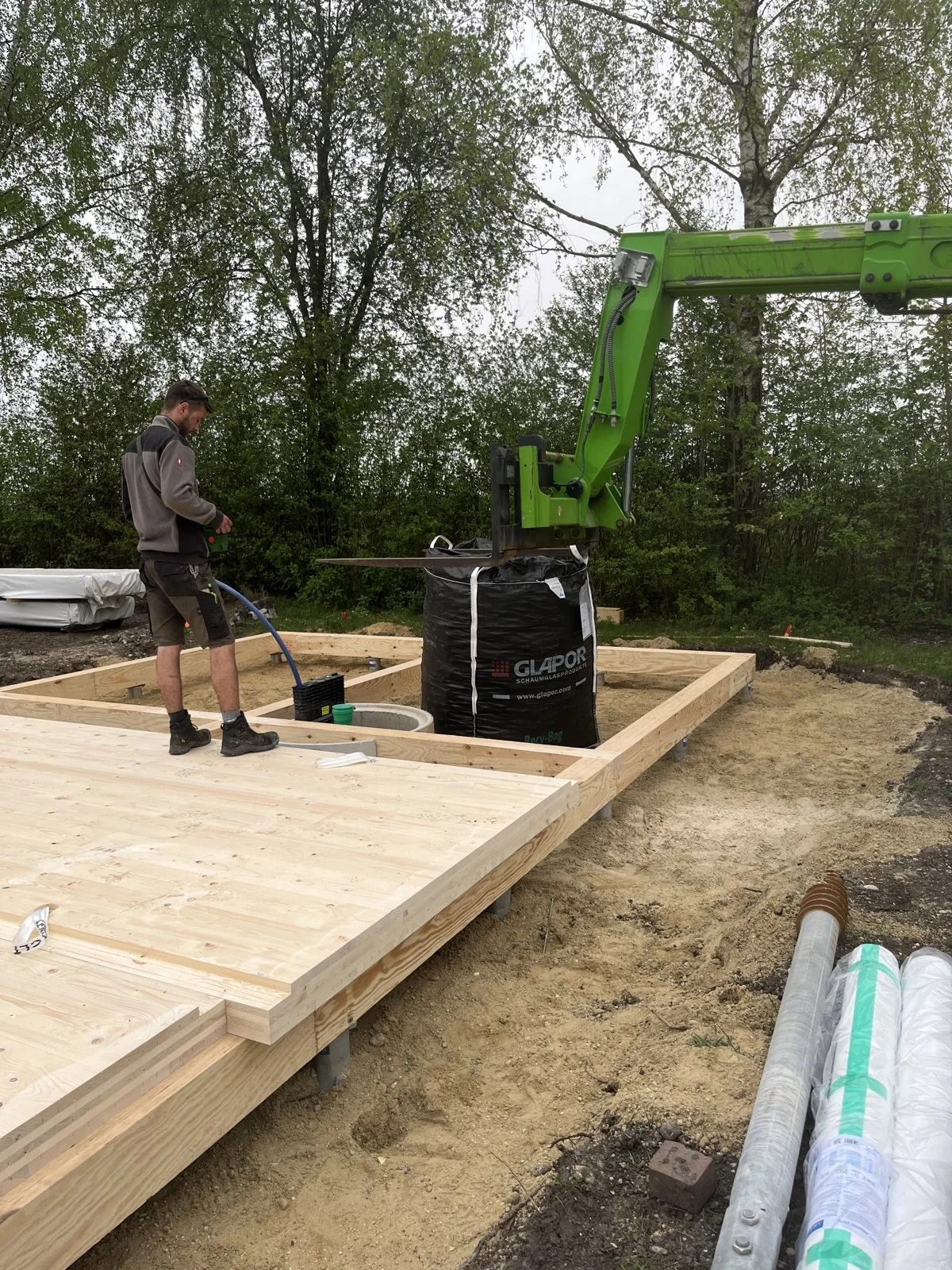 Montage der Holzbodenkonstruktion mit Mitarbeiter und Hebegerät
